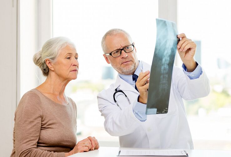 Lékař určuje cervikální osteochondrózu u pacienta pomocí radiografie